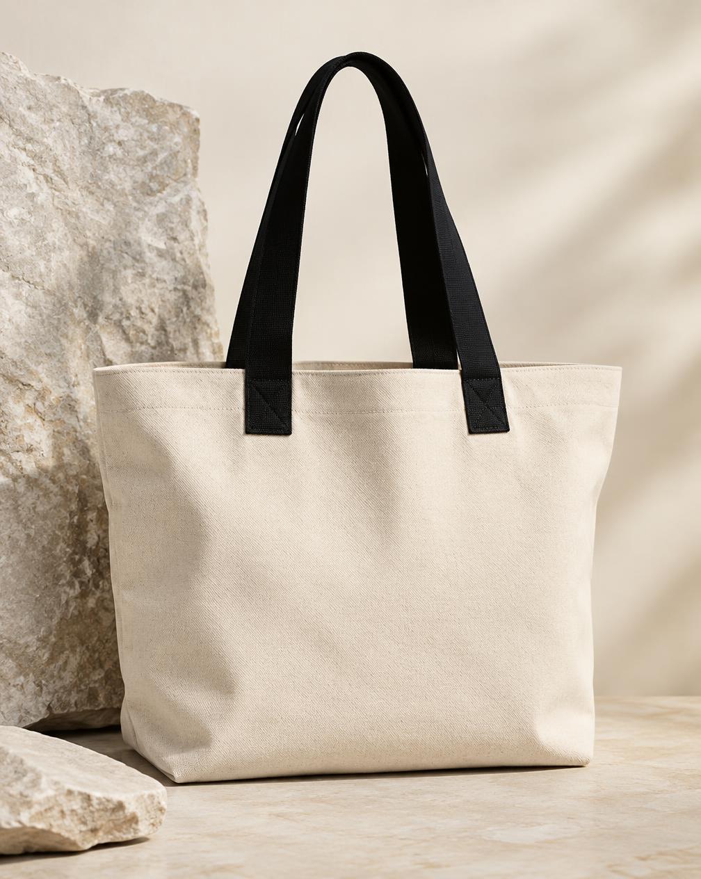 Tote bag en toile naturelle à anses noires sur pierre claire